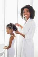 Pretty mother brushing her daughters hair