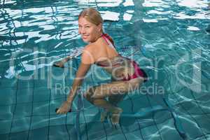 Fit happy blonde using underwater exercise bike