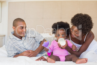 Happy parents with baby girl on their bed