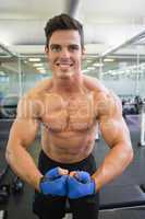 Shirtless muscular man flexing muscles in gym