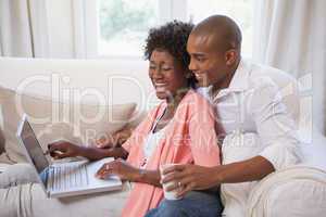 Happy couple relaxing together on the couch using laptop having