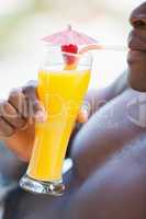 Shirtless man drinking orange cocktail