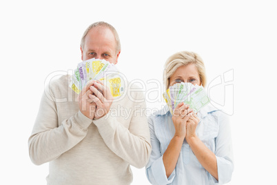 Happy mature couple smiling at camera showing money