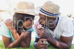 Happy couple lying in garden together smelling flowers