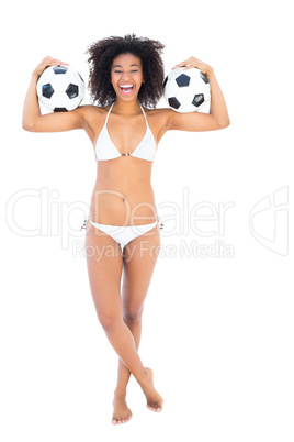 Excited fit girl in white bikini holding football