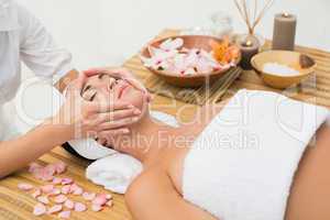 Peaceful brunette enjoying a face massage