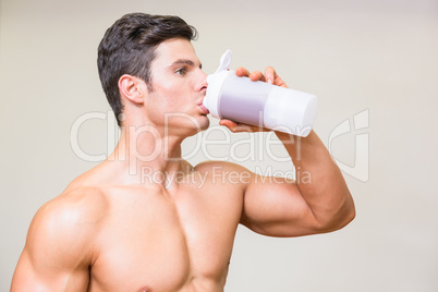 Close-up of a sporty young man drinking protein