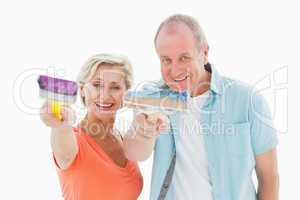 Happy older couple holding paintbrushes