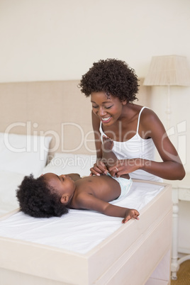 Happy mother with baby girl on changing table