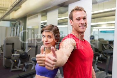 Fit attractive couple smiling at camera showing thumbs up