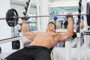 Muscular man lifting barbell in gym