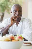 Happy man in bathrobe having breakfast on terrace