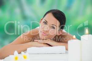 Beautiful brunette relaxing on massage table smiling at camera