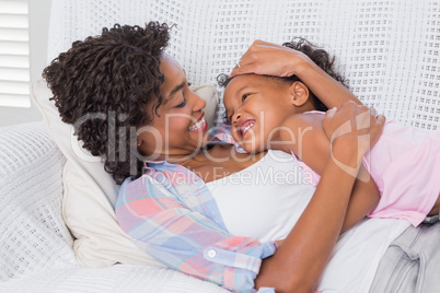 Cute daughter lying with mother on the sofa