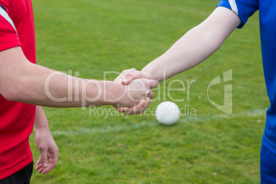 Football players in blue and red shaking hands