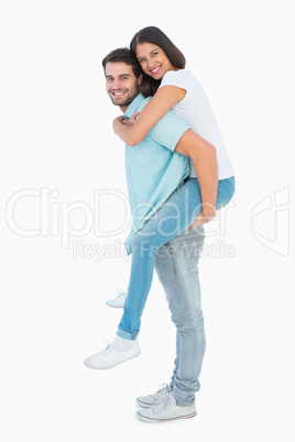 Happy casual man giving pretty girlfriend piggy back