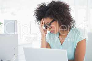 Stressed hipster businesswoman working on laptop