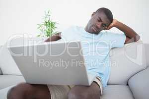 Casual man sitting on sofa using laptop