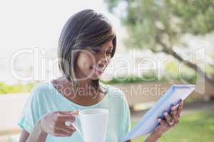 Pretty woman having her coffee outside using tablet pc