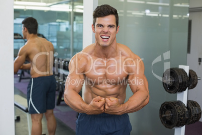 Shirtless muscular man flexing muscles in gym