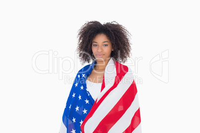 Pretty girl wrapped in american flag looking at camera