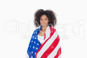 Pretty girl wrapped in american flag looking at camera