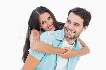 Happy casual man giving pretty girlfriend piggy back