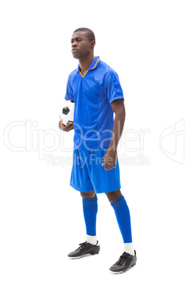 Football player in blue standing and holding ball