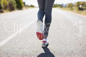 Fit woman running up the open road