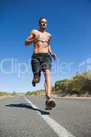 Athletic man jogging on open road with monitor around chest