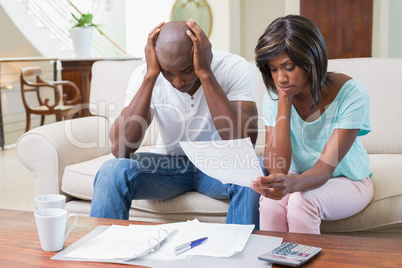 Stressed couple calculating bills on the couch