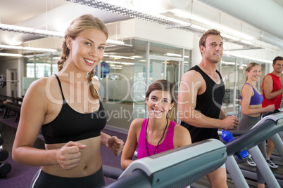 Trainer and clients smiling at camera on the treadmill