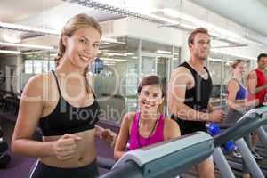 Trainer and clients smiling at camera on the treadmill