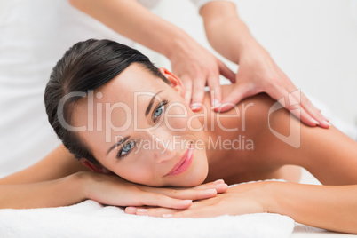 Beautiful brunette enjoying a shoulder massage smiling at camera