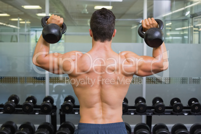 Muscular man lifting kettle bells in gym