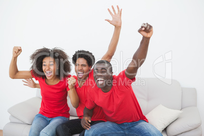 Football fans sitting on couch cheering together