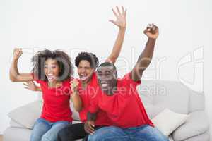 Football fans sitting on couch cheering together