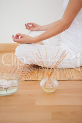 Peaceful woman sitting in lotus pose on bamboo mat