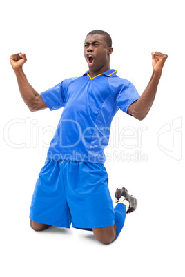 Excited football player in blue cheering on his knees