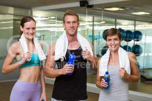 Fit man and women smiling at camera in studio