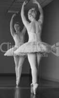 Graceful ballerina standing en pointe in front of mirror