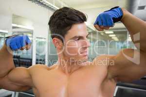 Shirtless muscular man flexing muscles in gym