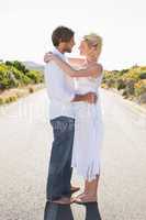 Attractive couple embracing barefoot on the road