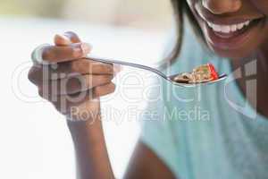 Smiling woman eating cereal outside