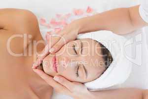 Attractive young woman receiving facial massage at spa center