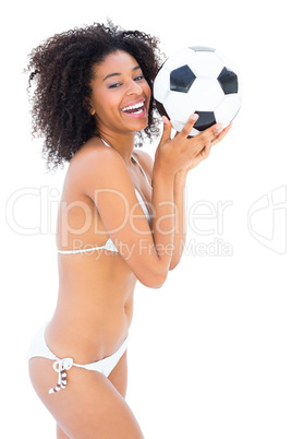 Smiling fit girl in white bikini holding football