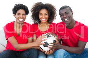 Happy football fans in red holding ball together