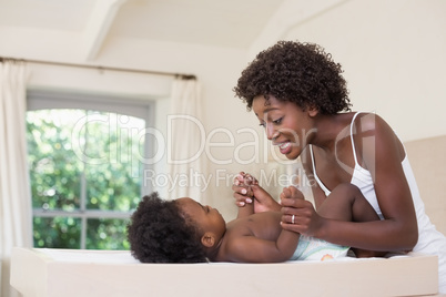 Happy mother with baby girl on changing table