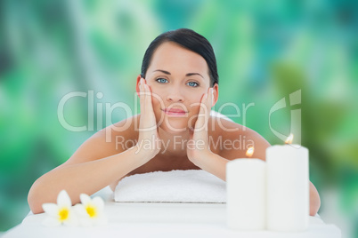 Beautiful brunette relaxing on massage table smiling at camera