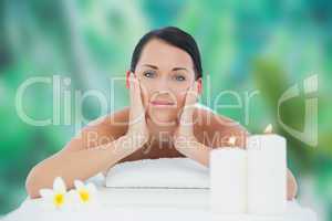 Beautiful brunette relaxing on massage table smiling at camera